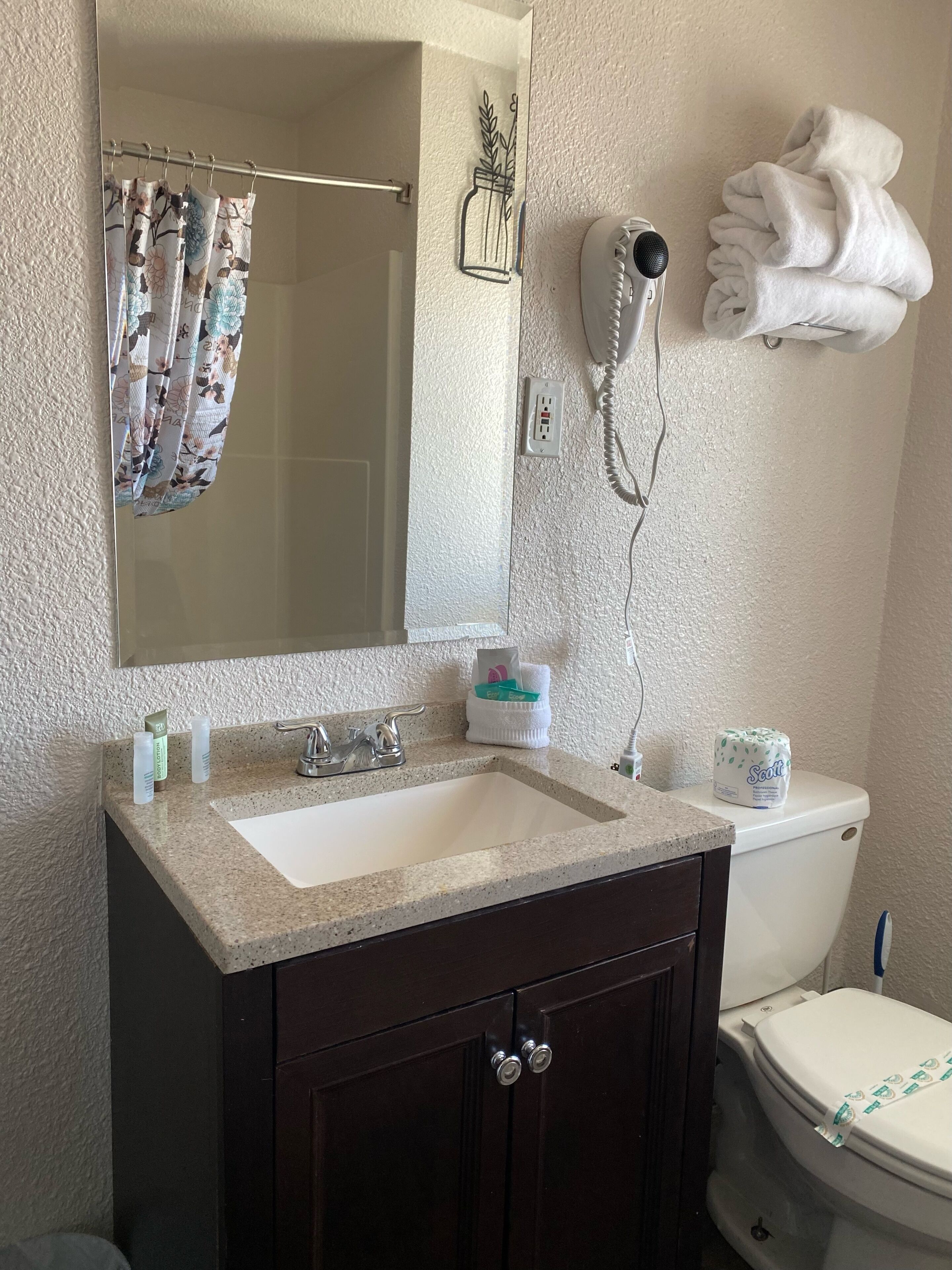 A bathroom with a sink, mirror, towel rack, and toilet.