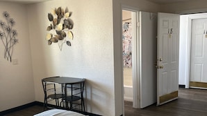 Makuuhuoneessa on suuri sänky, pieni pöytä tuoleineen, koristeellinen seinäelementti ja ovi, joka johtaa toiseen huoneeseen.
