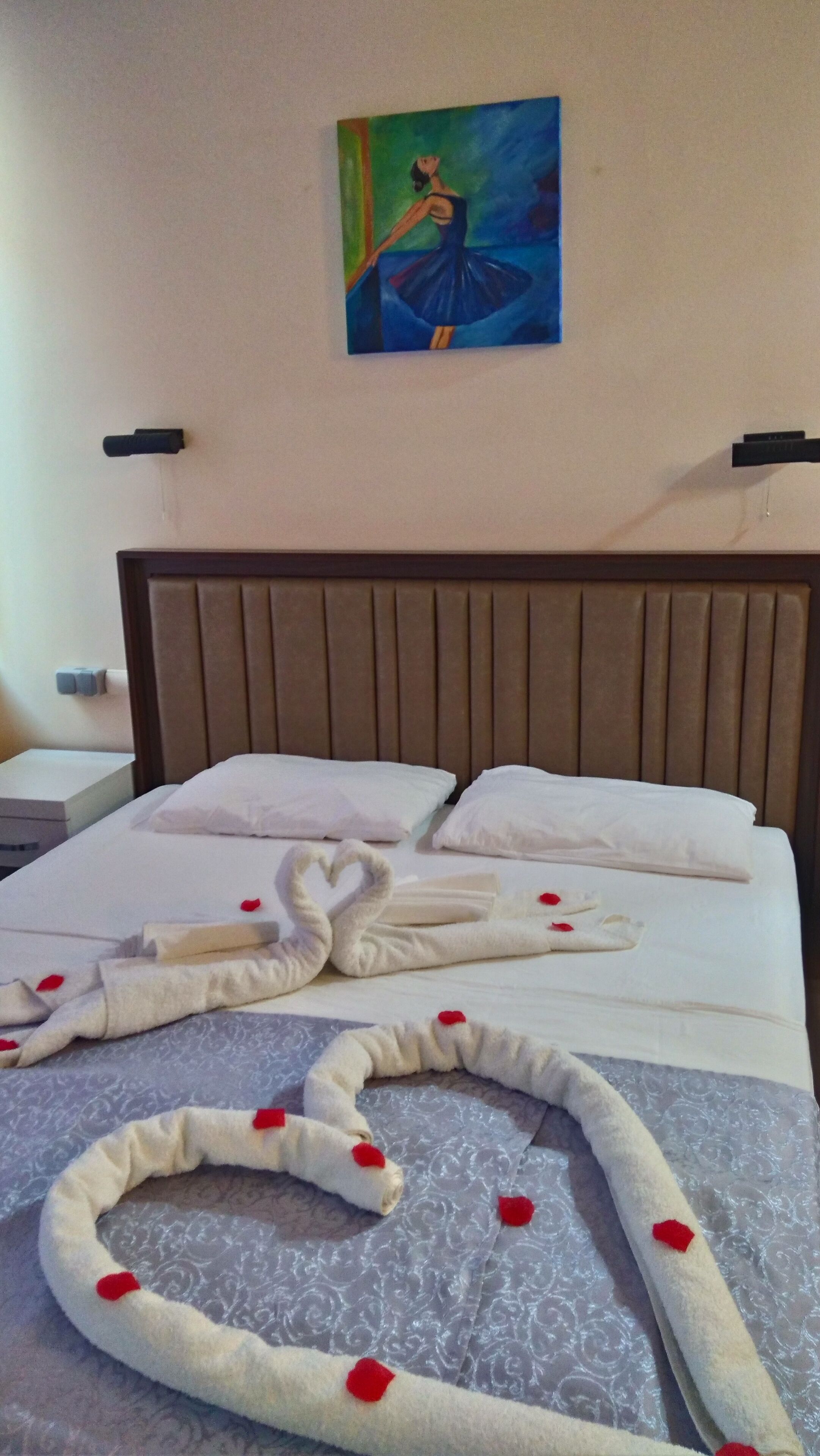 Una habitación de hotel con una cama bien hecha, un cuadro en la pared y un cabecero.