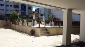 An outdoor area with a tiled floor, a staircase, and a railing. - Ed. Bosque das Azaleias (Salvador)