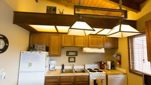 Una cocina con armarios de madera, refrigerador, estufa, pileta y microondas.