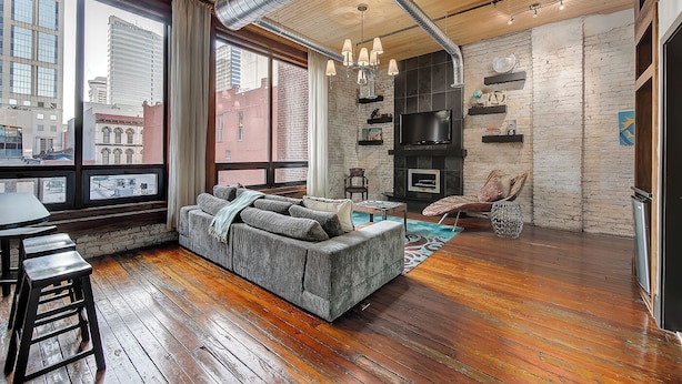 A modern living room with a large window, a fireplace, and a city view.