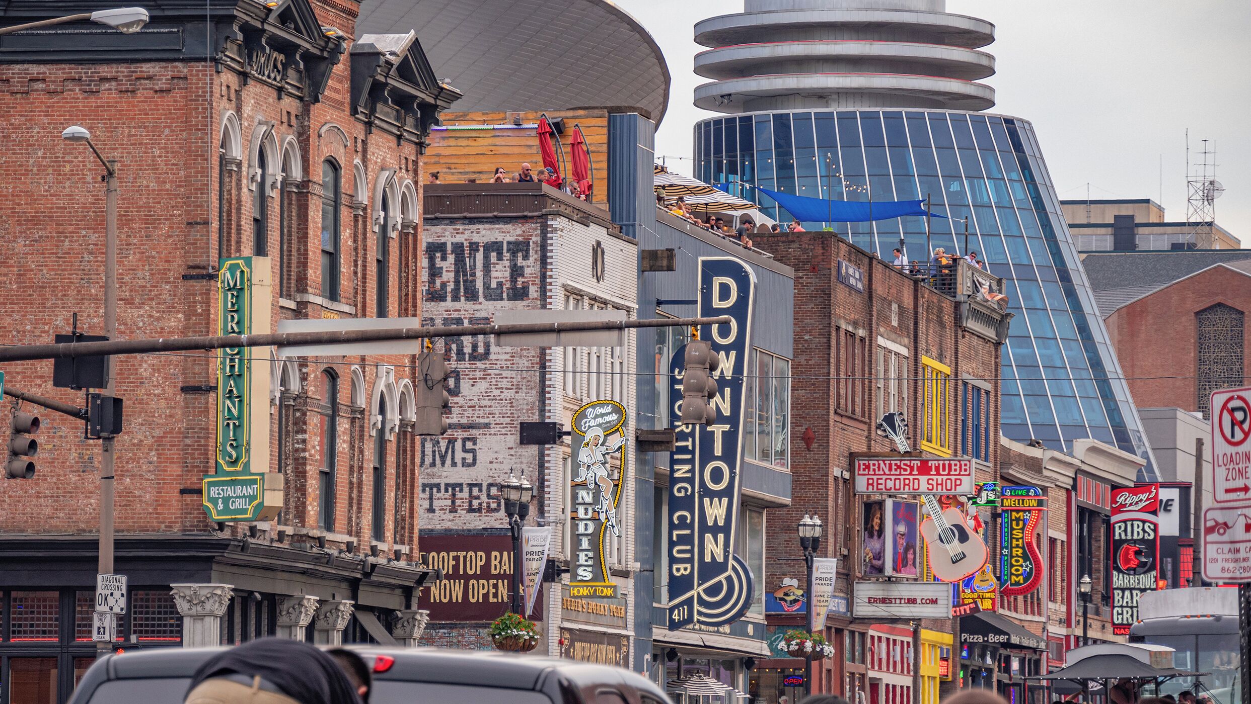 A street lined with various businesses including a record shop, a bar, and a restaurant.