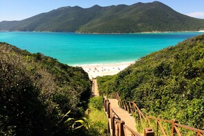 A wooden staircase leading to a beach with turquoise water and green hills in the background. - BEACH, ARRAIAL DO CABO! PROVIDING THE BEST FOR YOUR FAMILY FOR OVER 10 YEARS  (ARRAIAL DO CABO)