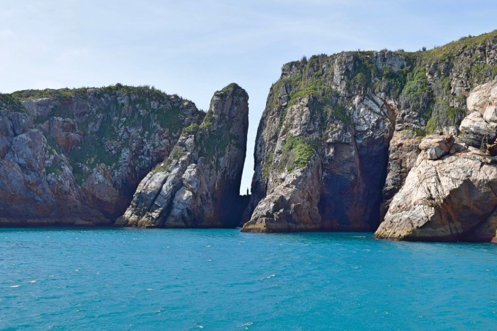 A coastal landscape with two prominent rock formations and a narrow waterway between them.