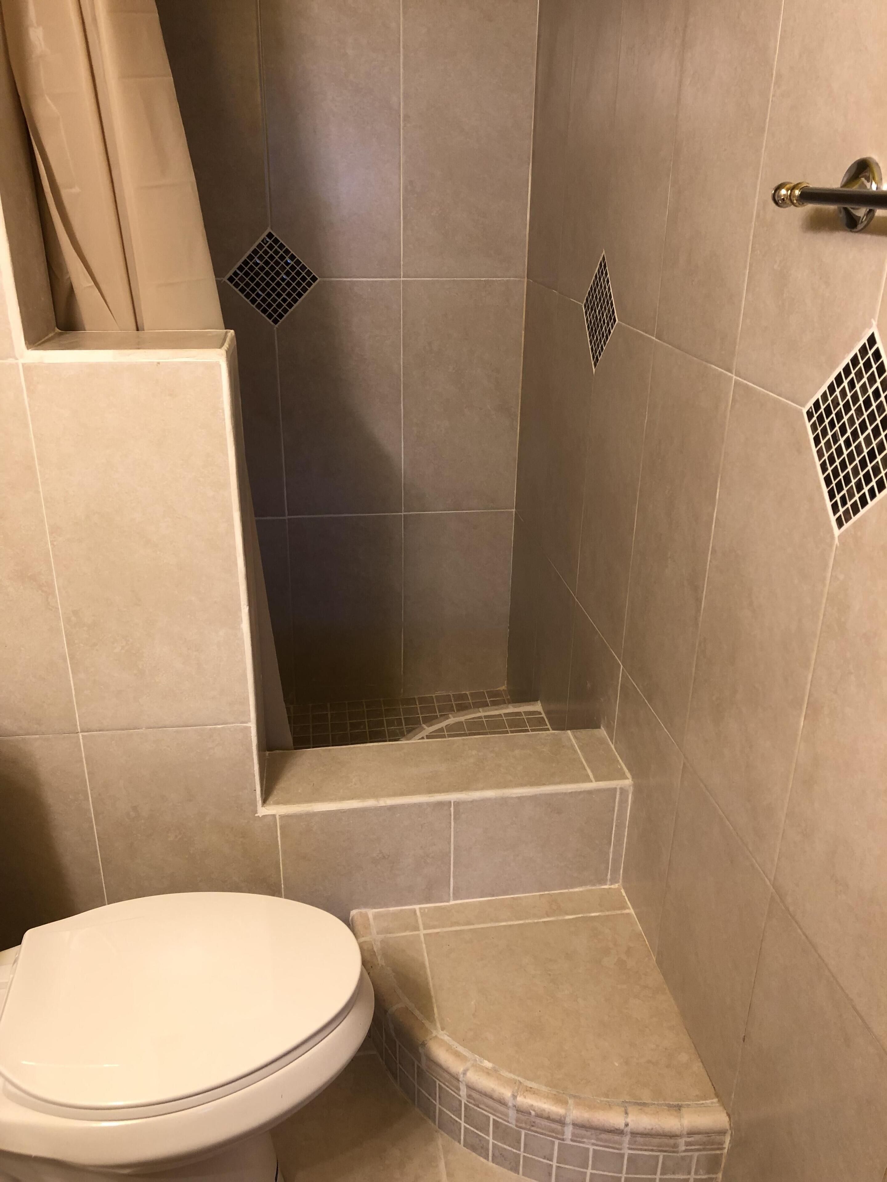 Ein Badezimmer mit Toilette, einer Duschkabine mit Fliesenboden und einer Duschvorhang.