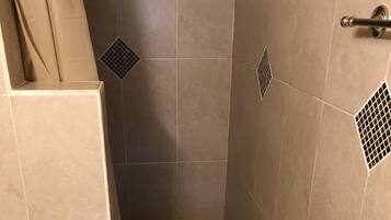 Ein Badezimmer mit Toilette, einer Duschkabine mit Fliesenboden und einer Duschvorhang.