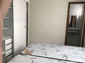 Une chambre à coucher comprenant un lit, une armoire et une salle de bain avec un lavabo et un miroir.