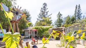 Un patio rústico al aire libre con un molino de madera, zona de estar y plantas en macetas.
