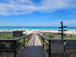 A wooden boardwalk leading to a beach with clear skies.