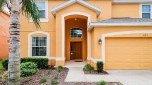 A two-story house with a yellow facade, a brown front door, and a garage with the number 681.