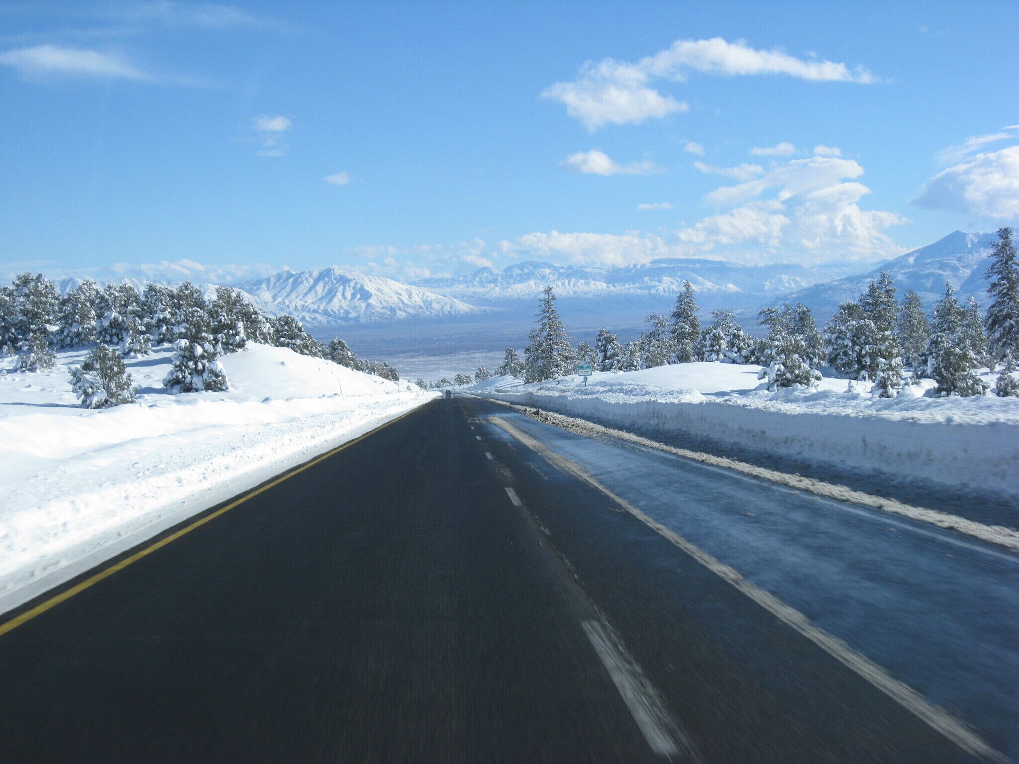 A snow-covered road with mountains in the background.