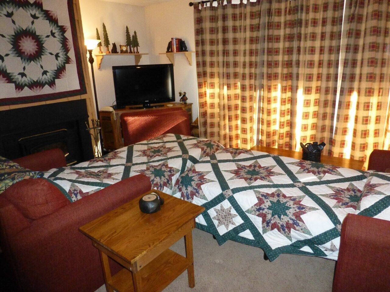 A cozy living room with a large bed, a television, and a fireplace.