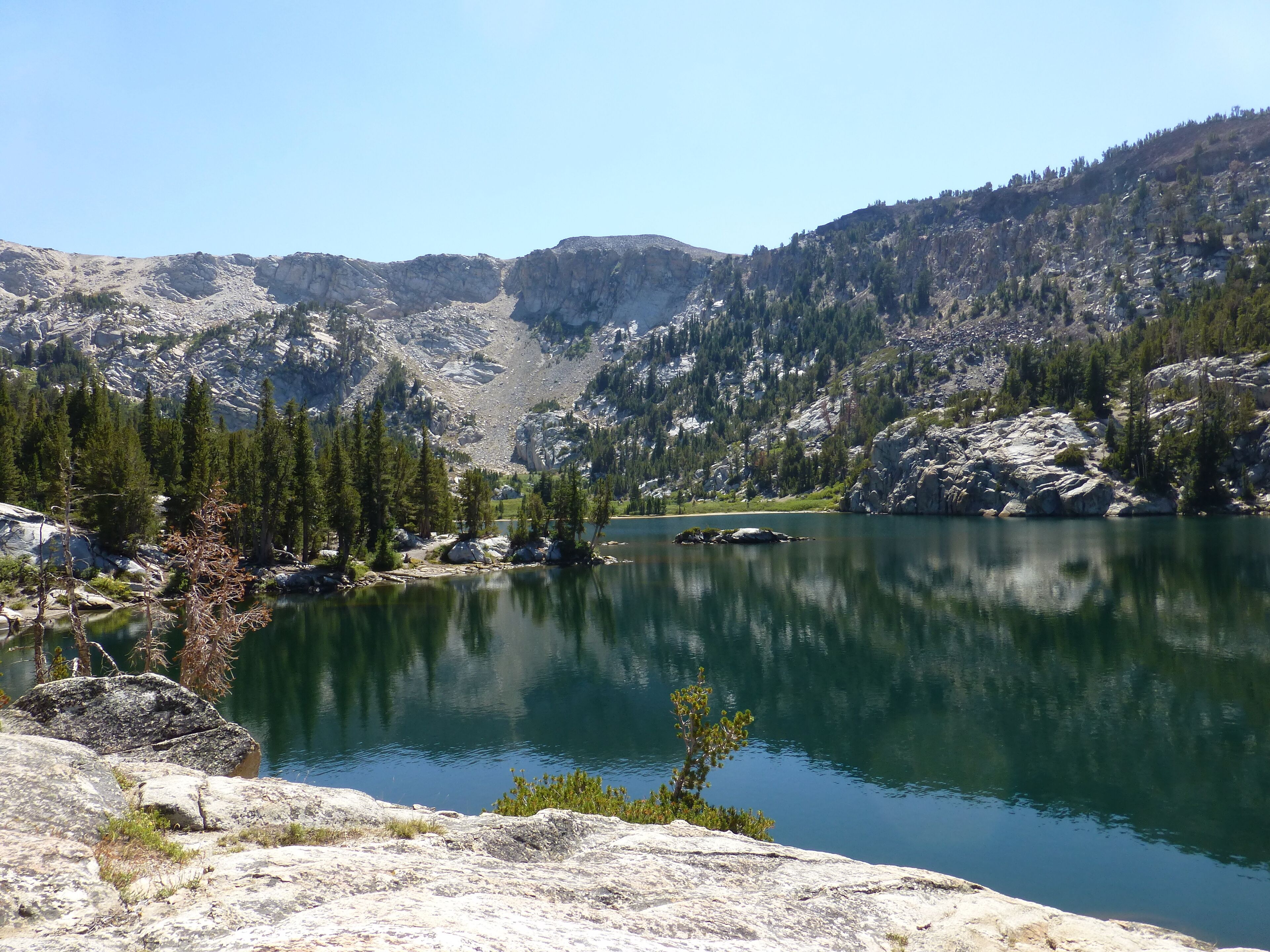 Un lago sereno rodeado de montañas rocosas y bosques densos.