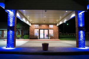 A building with a brick facade, a covered entrance, and a potted plant in the foreground.