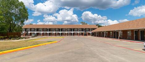 A motel with a central courtyard, multiple rooms, and a brick facade.