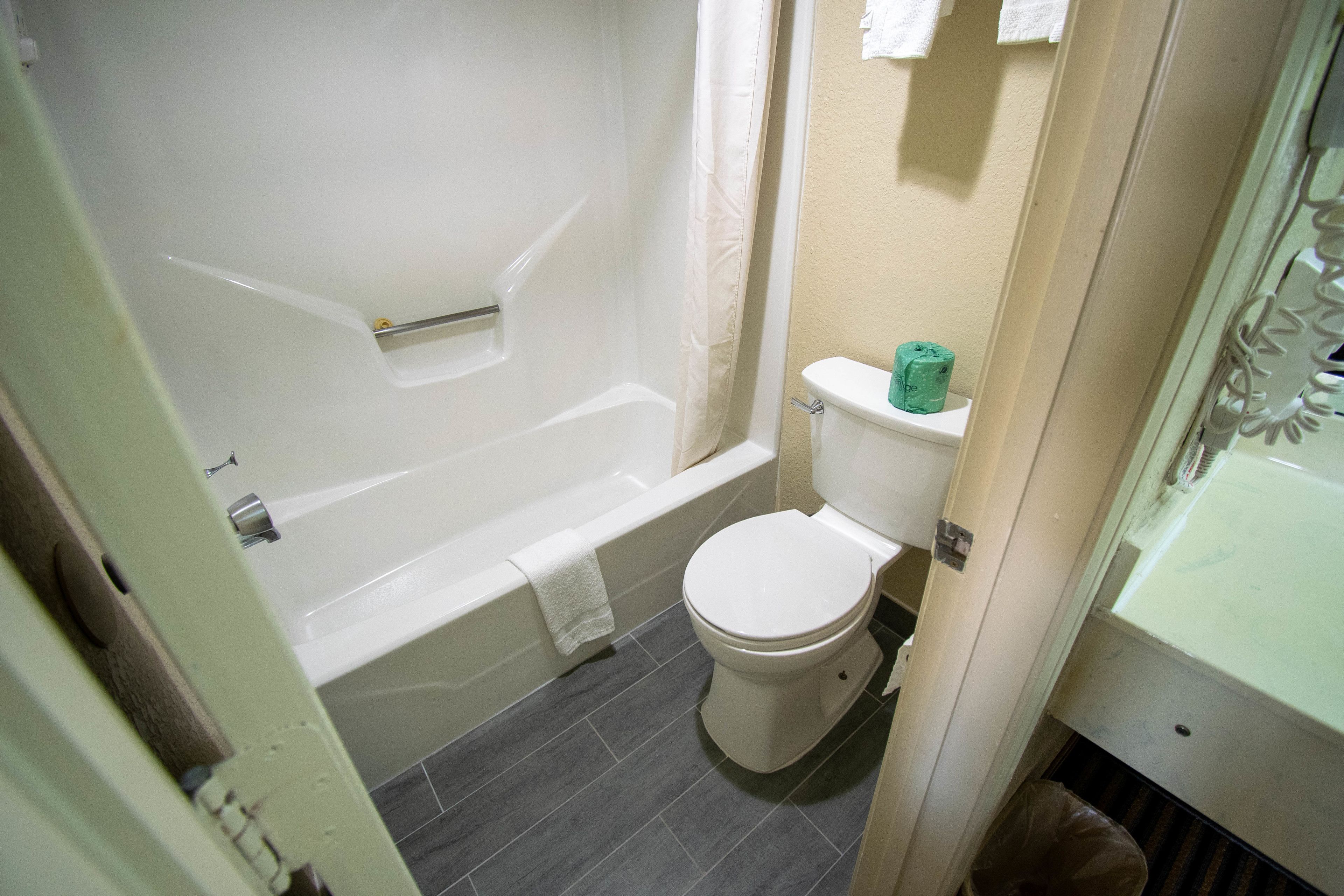 A bathroom with a bathtub, toilet, and a shower curtain.