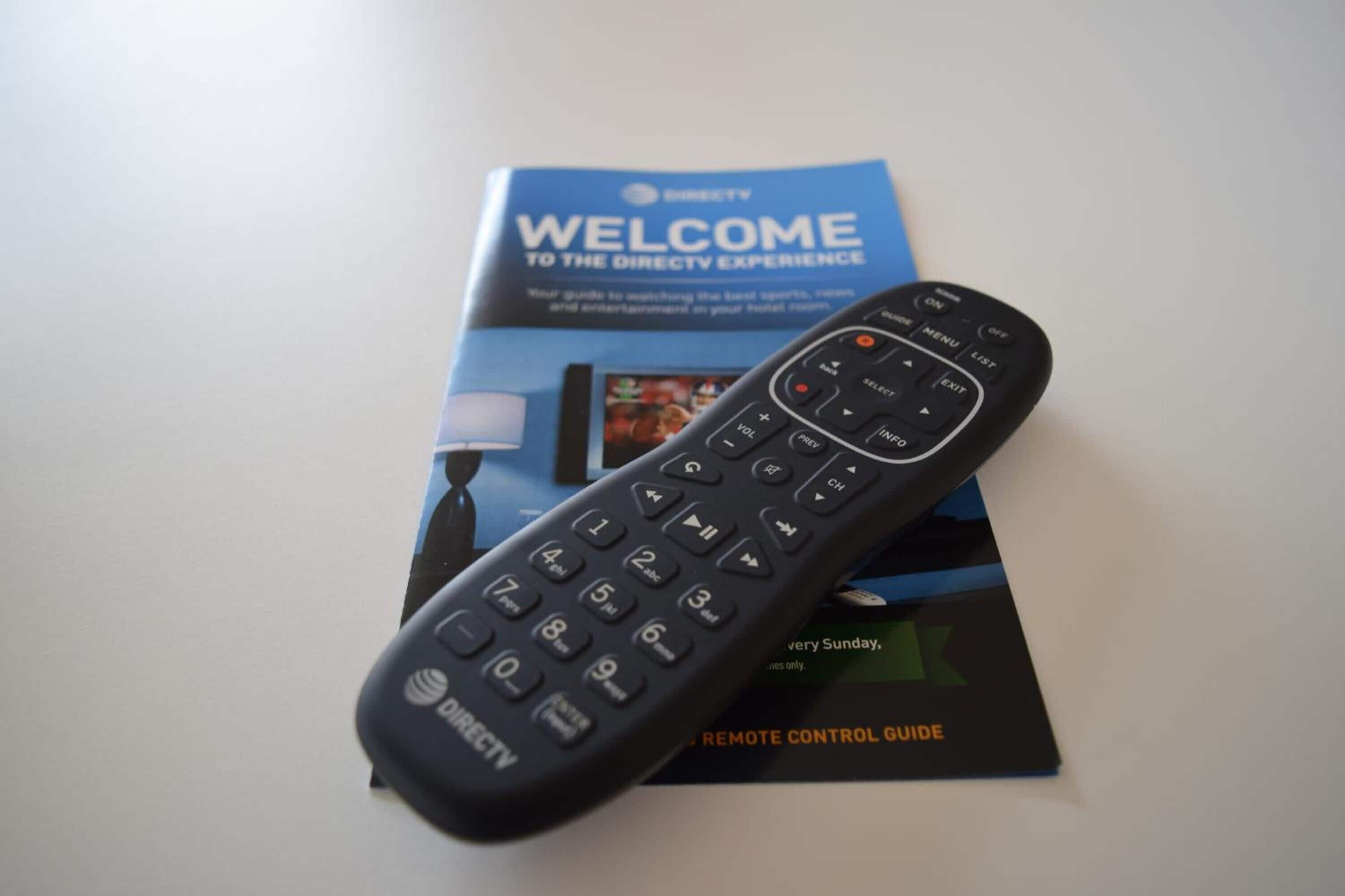 Un control remoto de DIRECTV y una guía de bienvenida de DIRECTV sobre una mesa.