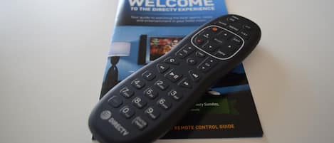 Un control remoto de DIRECTV y una guía de bienvenida de DIRECTV sobre una mesa.