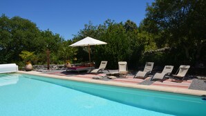 Ein Schwimmbecken mit Liegestühlen und einem Sonnenschirm.