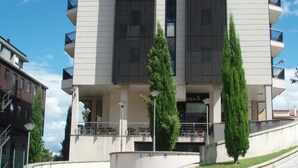 Un bâtiment moderne doté d’un toit plat, de nombreux balcons et d’une entrée centrale.