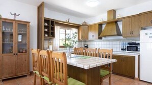 A kitchen with wooden cabinets, a tiled backsplash, and a dining table with chairs. - Home2Book Garachico Ocean View & Wifi (Las Cruces)