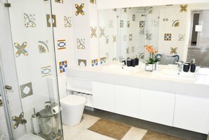 Un baño moderno con un lavamanos blanco, un espejo grande y azulejos decorativos en las paredes.