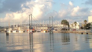 Eine Brücke über einen Jachthafen mit Booten, unter einem klaren Himmel und ruhiger Wasserfläche.