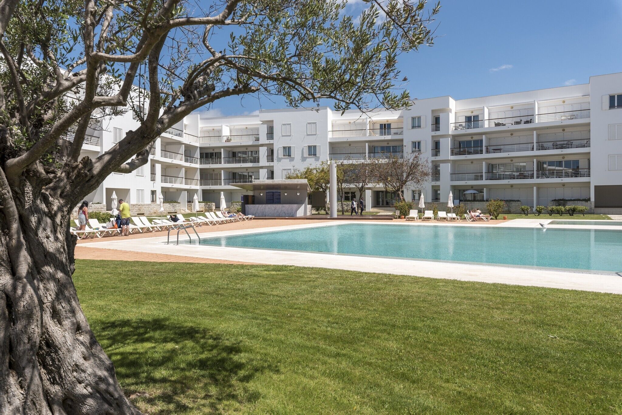 Un hôtel moderne doté d’une piscine, de nombreux balcons et d’une pelouse bien entretenue.