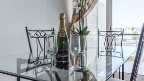 Ein Glastisch mit einer Champagnerflasche, zwei Gläsern und einem Topf mit einer Orchidee.