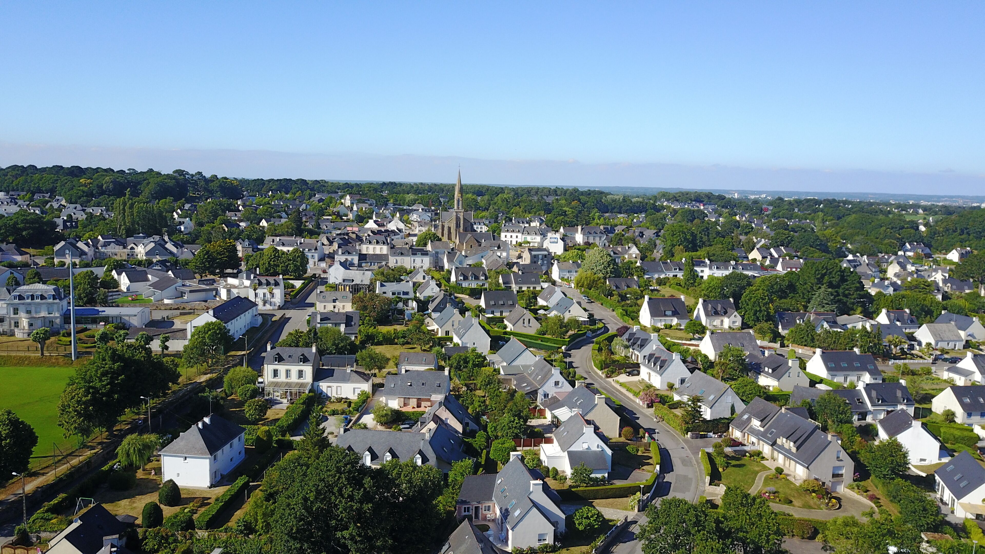 A residential area with houses, a church spire, and a clear sky.