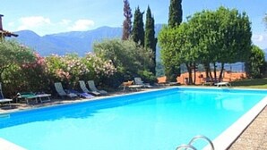 A swimming pool with lounge chairs and a clear view of mountains in the background.