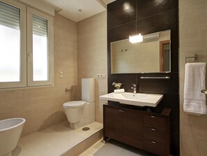 A modern bathroom with a toilet, sink, and mirror. - ChezmoiHomes La Belle Epoque (Granada)