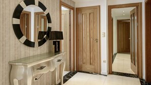 A hallway with a wooden door, a glass console table with a lamp, and a large mirror on the wall. - ChezmoiHomes La Belle Epoque (Granada)