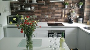 Een moderne keuken met een tegelachterwand, witte keukenkastjes en hanglampen.