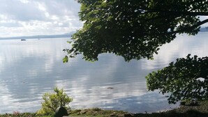 Een picknicktafel bij een meer, met een gazon en rotsen.