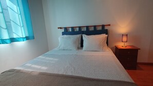A neatly made bed with white bedding, a wooden headboard, and a bedside table with a lamp. - Living sorrouded by vineards in Douro (Gestaco)