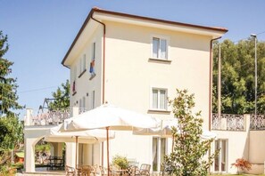 Ein zweistöckiges Gebäude mit Balkon, Außenbereich und einem weißen Sonnenschirm.