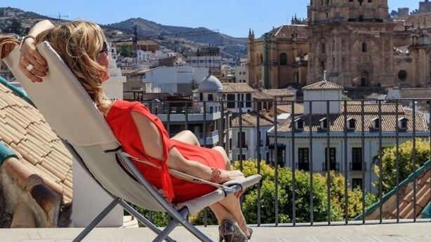A person relaxing on a sun lounger overlooking a historic building with a dome and bell tower. - ChezmoiHomes Trinidad Deluxe 1 (Granada)
