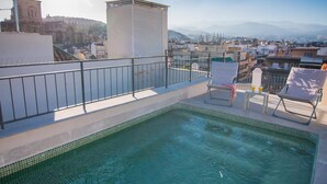 A rooftop pool with two lounge chairs and a table, overlooking a cityscape with mountains in the distance. - ChezmoiHomes Trinidad Deluxe 1 (Granada)