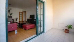 A spacious living area with a red sofa, a wooden dining table, and a television. - CARCAVELOS BEACH 2. A wonderful 2 bedroom (Carcavelos)