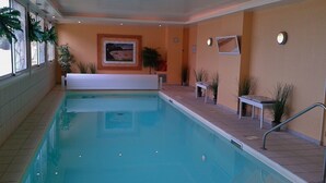 An indoor swimming pool with clear water, surrounded by tiled walls and a bench. - App. Les Roches d'Argent-Sea View, Beaches, Heated Indoor Pool. (Plestin-Les-Grèves)
