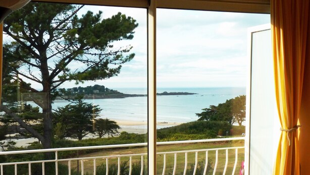 A balcony with a view of the sea, a table, and two chairs. - App. Les Roches d'Argent-Sea View, Beaches, Heated Indoor Pool. (Plestin-Les-Grèves)