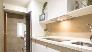 Una cocina moderna con armarios blancos, un refrigerador de acero inoxidable, un horno empotrado y un lavamanos con grifo.