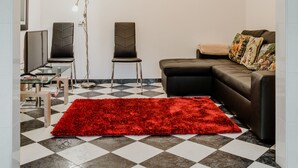 A living room with a checkered floor, a red rug, a sofa, two chairs, a chandelier, and an arched doorway. - Funchal City View Gardens I  (Funchal)