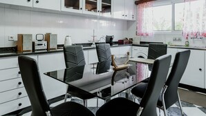 A modern kitchen with white cabinets, a black dining table, and four black chairs. - Funchal City View Gardens I  (Funchal)
