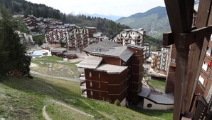 Un complejo turístico montañoso con edificios de varios pisos, un telesilla y una vista despejada del paisaje circundante.