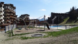Un parque infantil con columpios y un tobogán, rodeado por una valla.