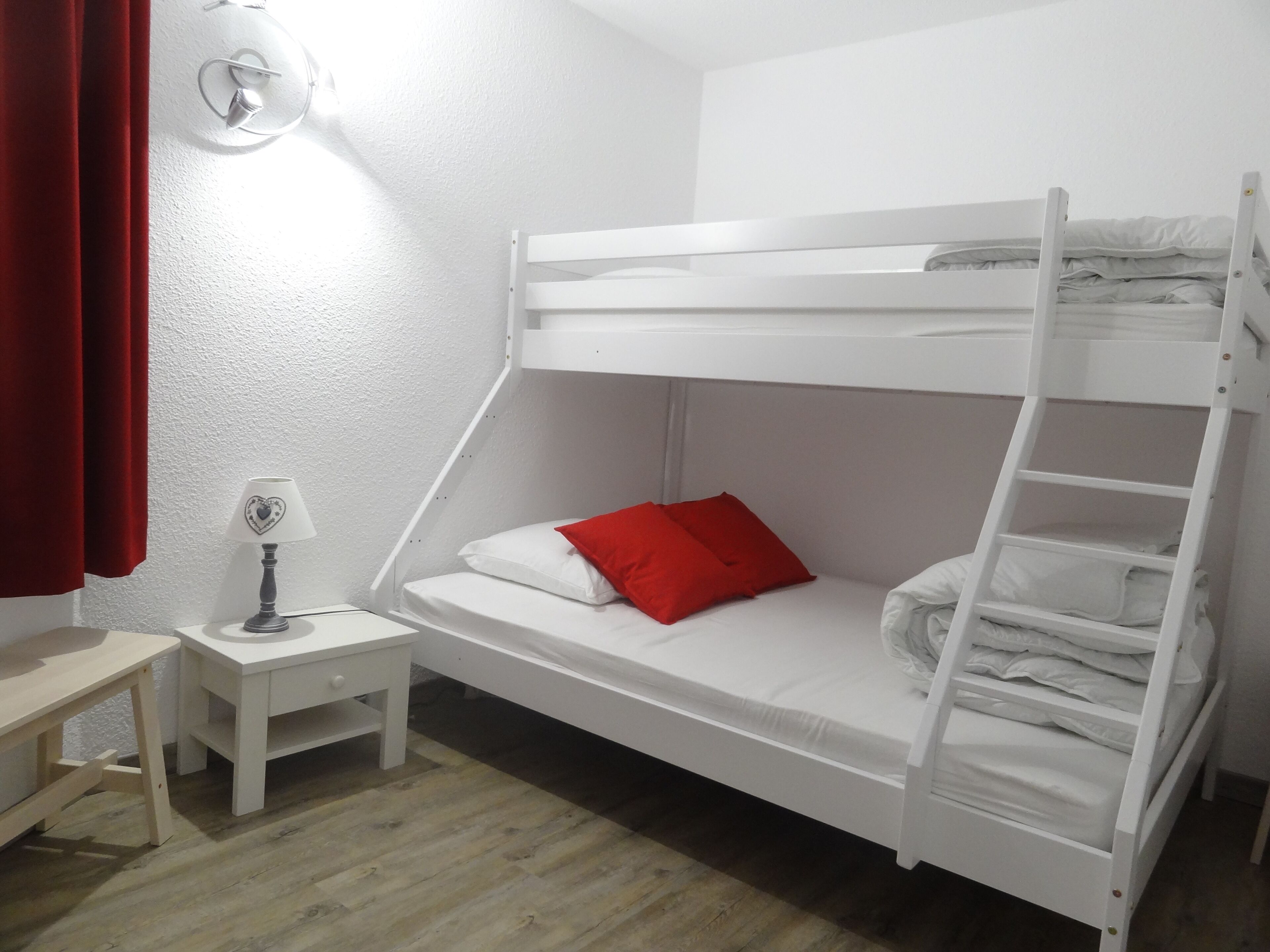 A bunk bed room with a desk and a lamp.