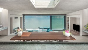 Ein moderner Essbereich mit großem Tisch, Sitzgelegenheiten und Blick aufs Wasser.
